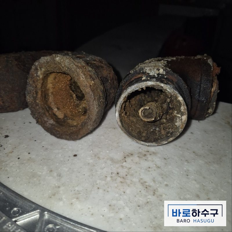 바닥에서 걷어낸 주철 배관 단면, 녹과 찌꺼기가 두껍게 덮인 작업 전 (군포 현장)